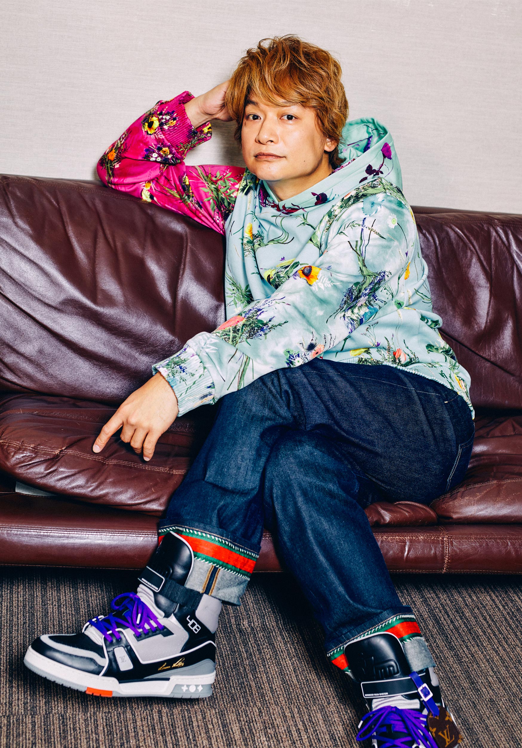 ソファーに座り、鮮やかなパーカーを着た香取慎吾さんの写真