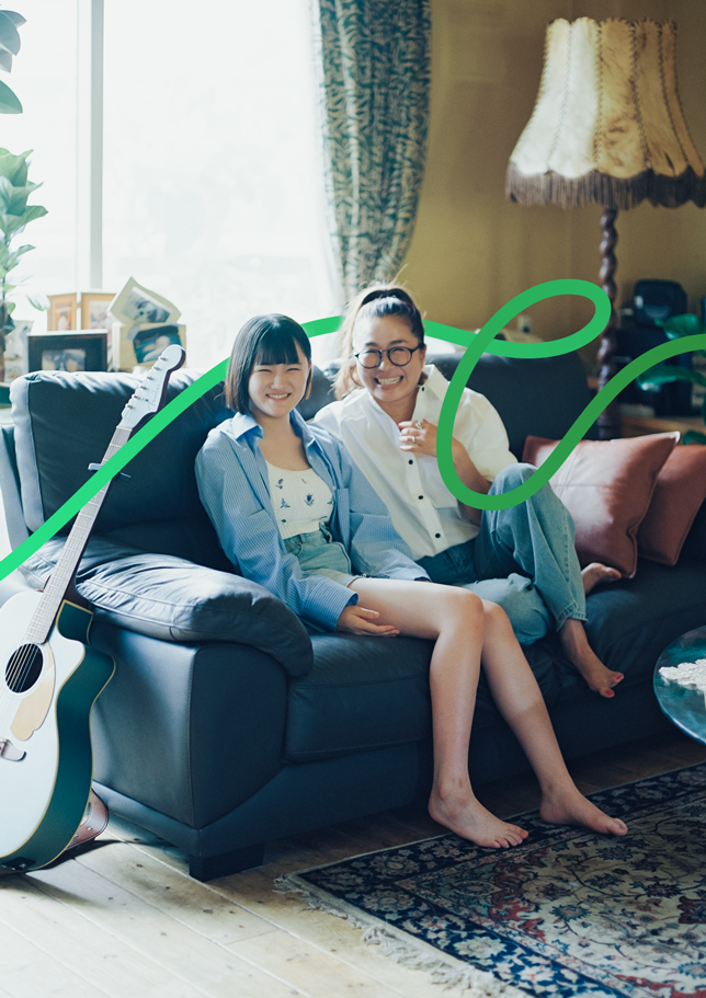 ファッションブランド プロデューサー Donoban Kaoriと娘のかりんちゃんが笑顔でソファーに座っている写真。