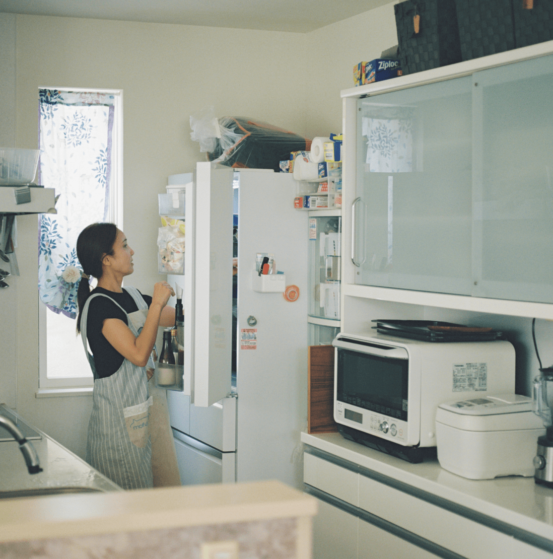 キッチンにある冷蔵庫を開けている女性。