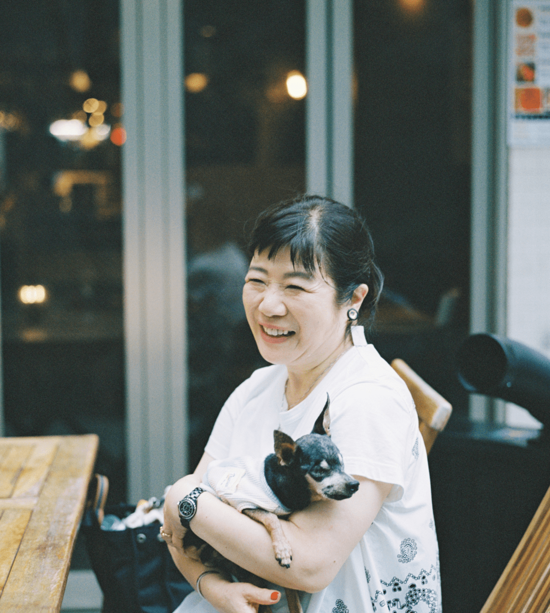 椅子に座っている笑顔で愛犬を抱えている女性。