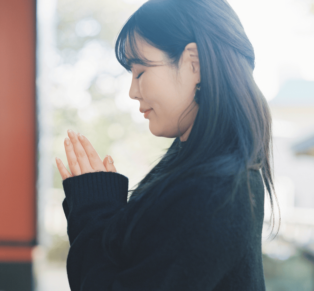 手を合わせてお祈りをしている女性。