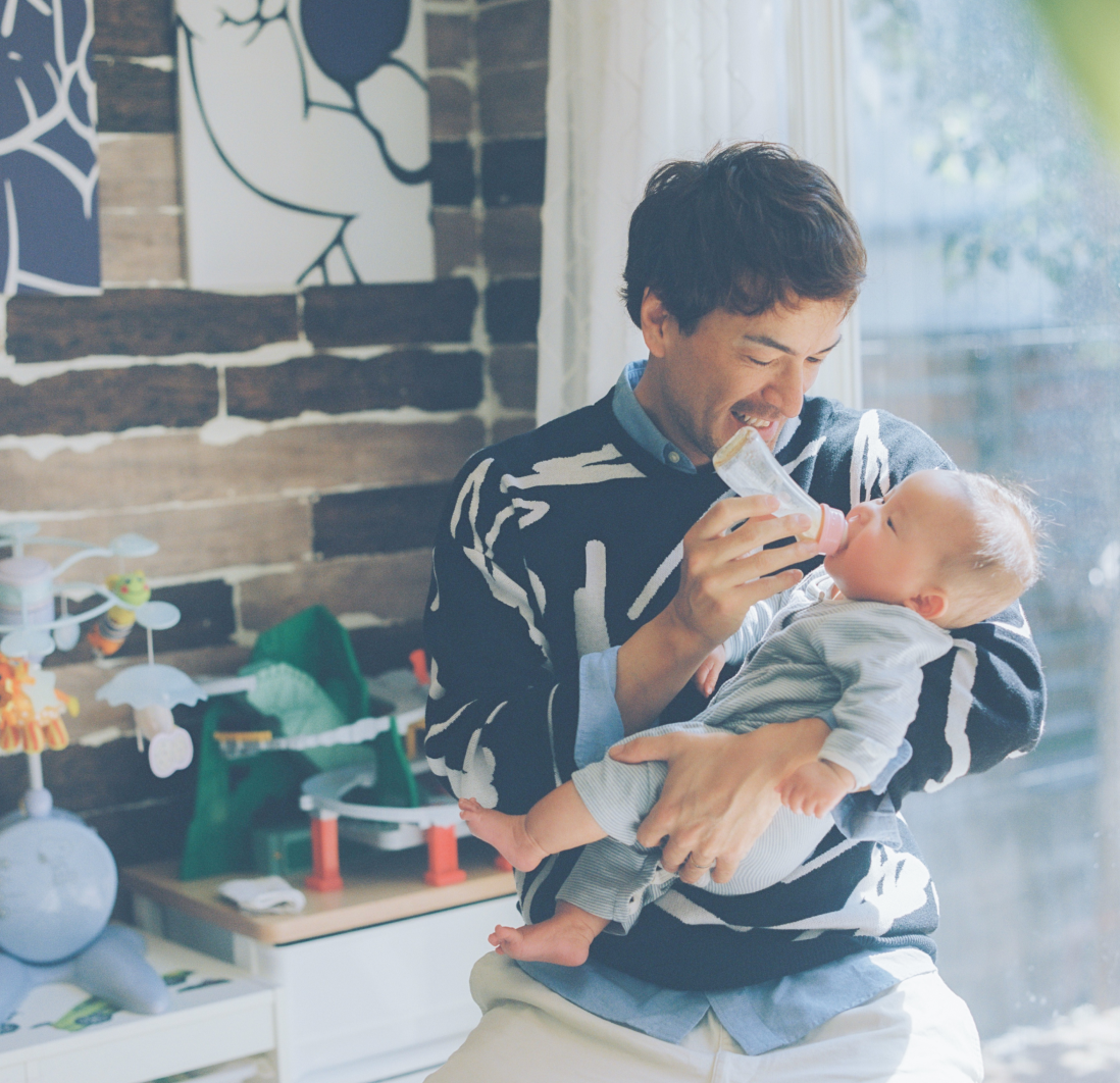 赤ちゃんに哺乳瓶からミルクをあげている男性。