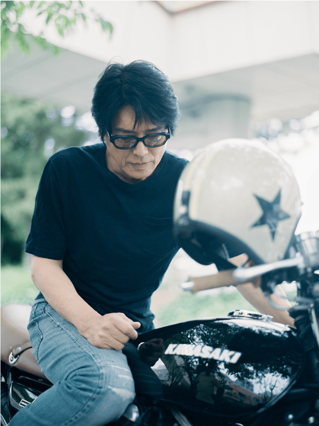 バイクにまたがり下向いてどこかを見つめる男性。