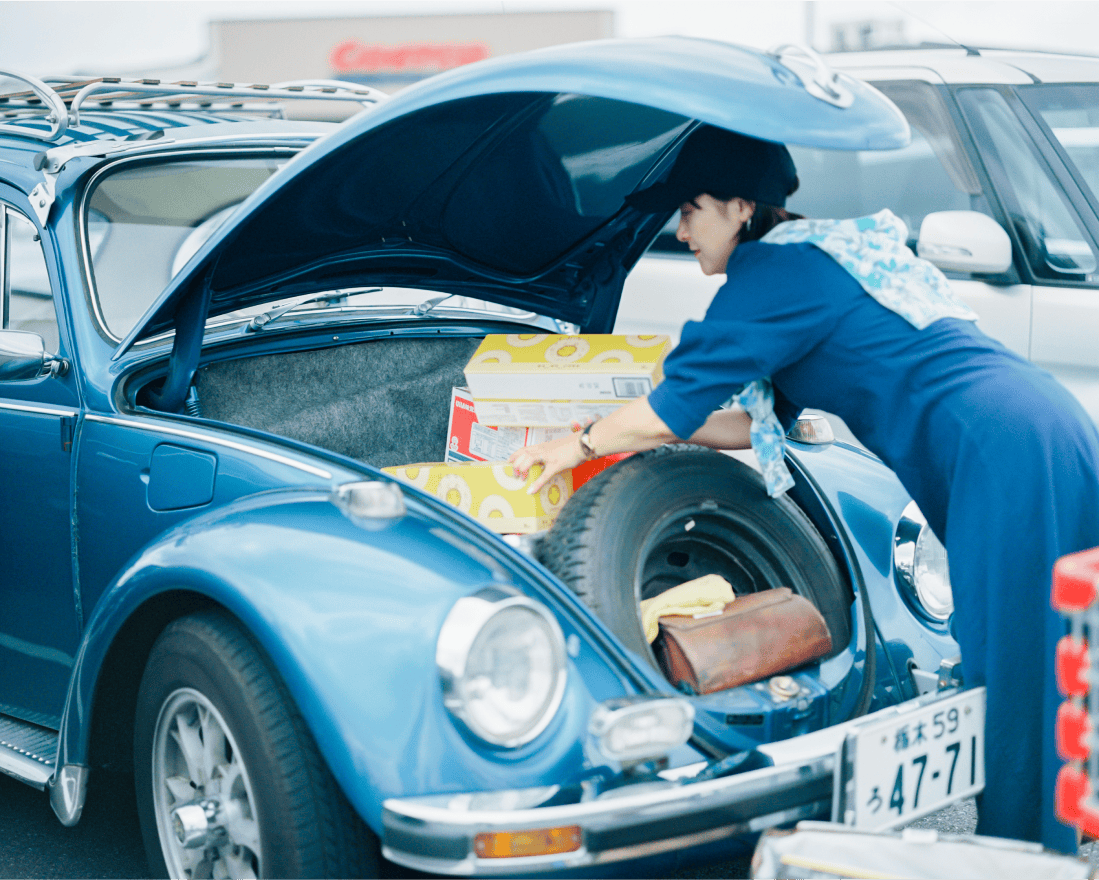 車のトランクに荷物を入れている女性。