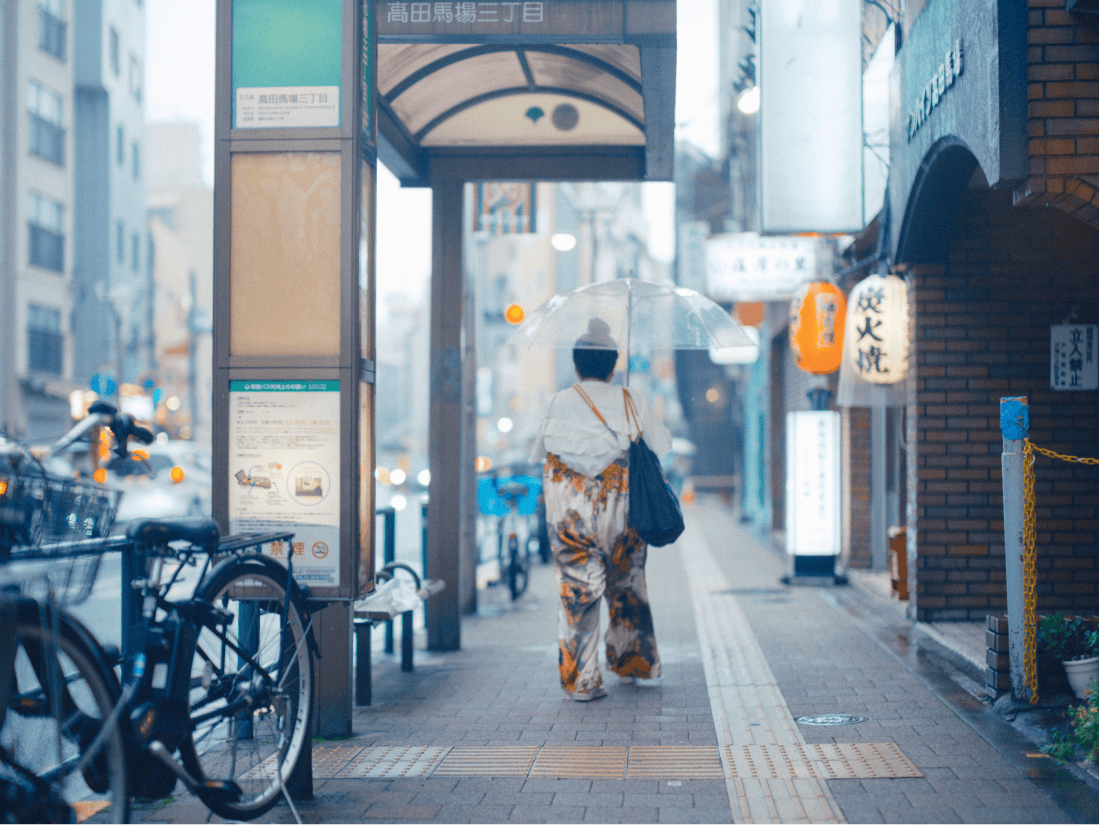 傘をさして街を歩く女性の後ろ姿。