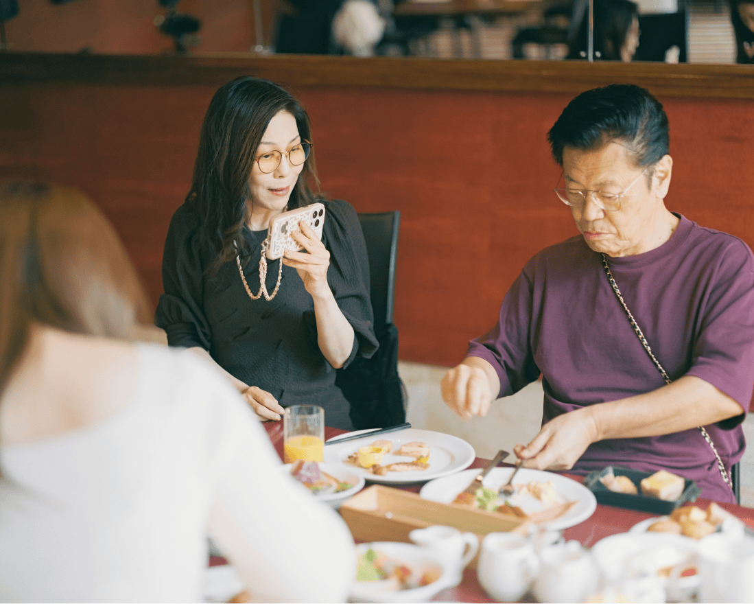 朝食に手をつけている男性を撮影している女性。