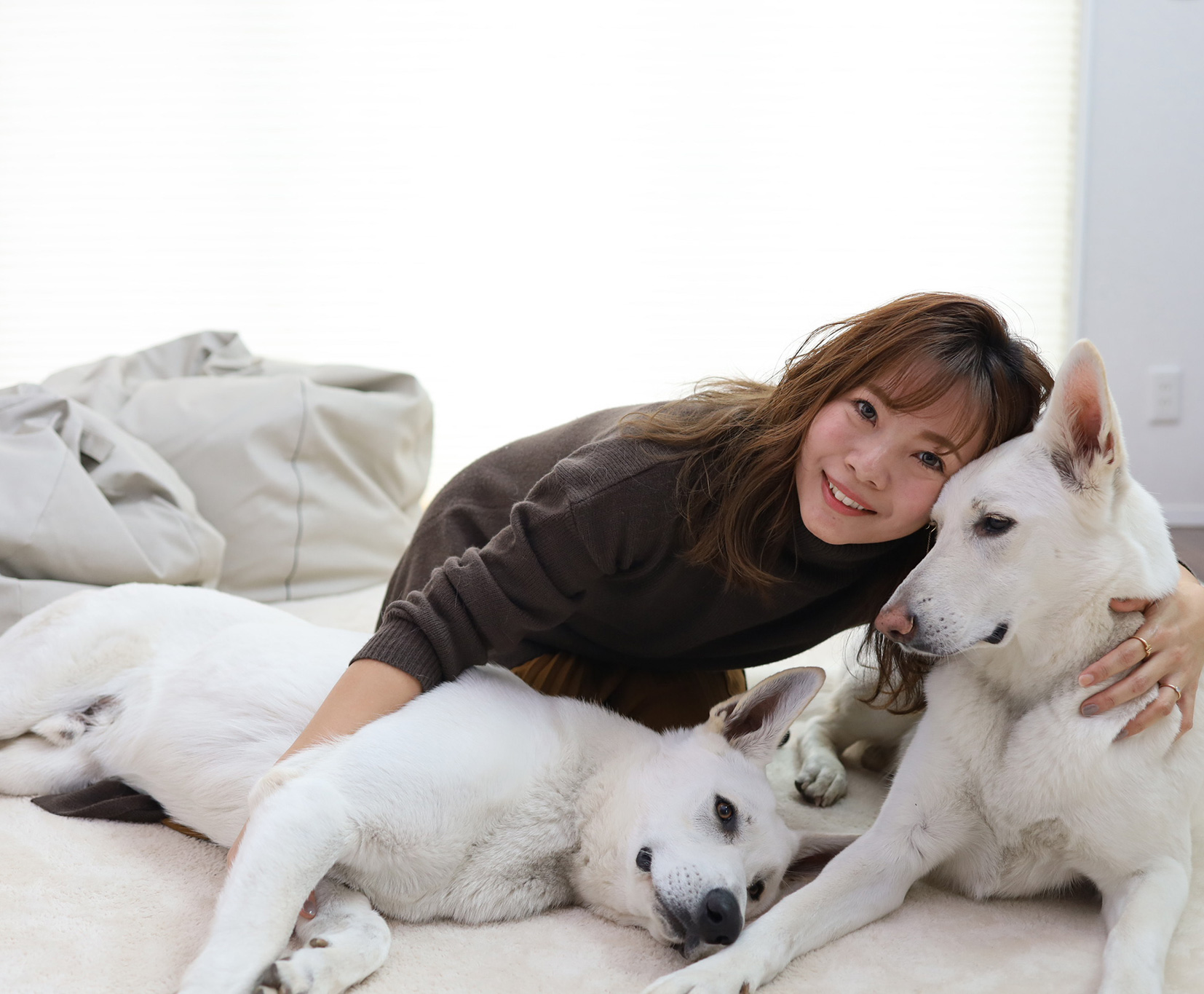 リラックスした愛犬二匹を抱きしめながら笑顔のyukikoさんの写真